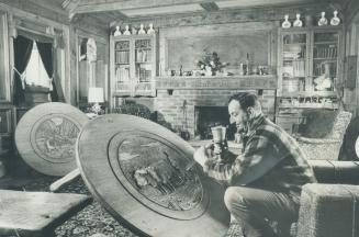 Basil self carves a farming scene in the top of a pine coffee table at his home in Nobleton, near Bolton