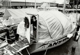 Mary Saunderson peers out from her 36-foot sloop Omega Answer, which has a plastic cover over the cockpit to give extra space and to keep the heat in during the winter