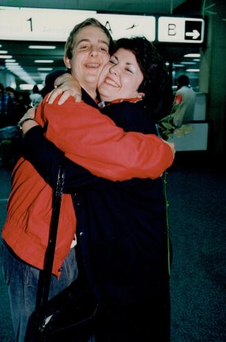 Margaret Schuman greets her son John, 17, with a hug and a rose at Pearson Airport last night