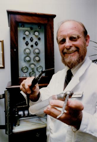 Dr. Barry Sessie holds 1912-era tools used for painless dentistry.