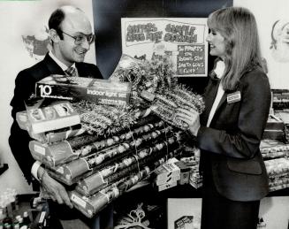 Sample auction: Joe Shanab, purchasing vice-president of Shoopers Drug Mart, and Christine Cattell, a TV commercial spokesman, get ready to auction off merchandise samples to the drug chain's head offfice staff, to raise money for The Star Santa Claus Fund