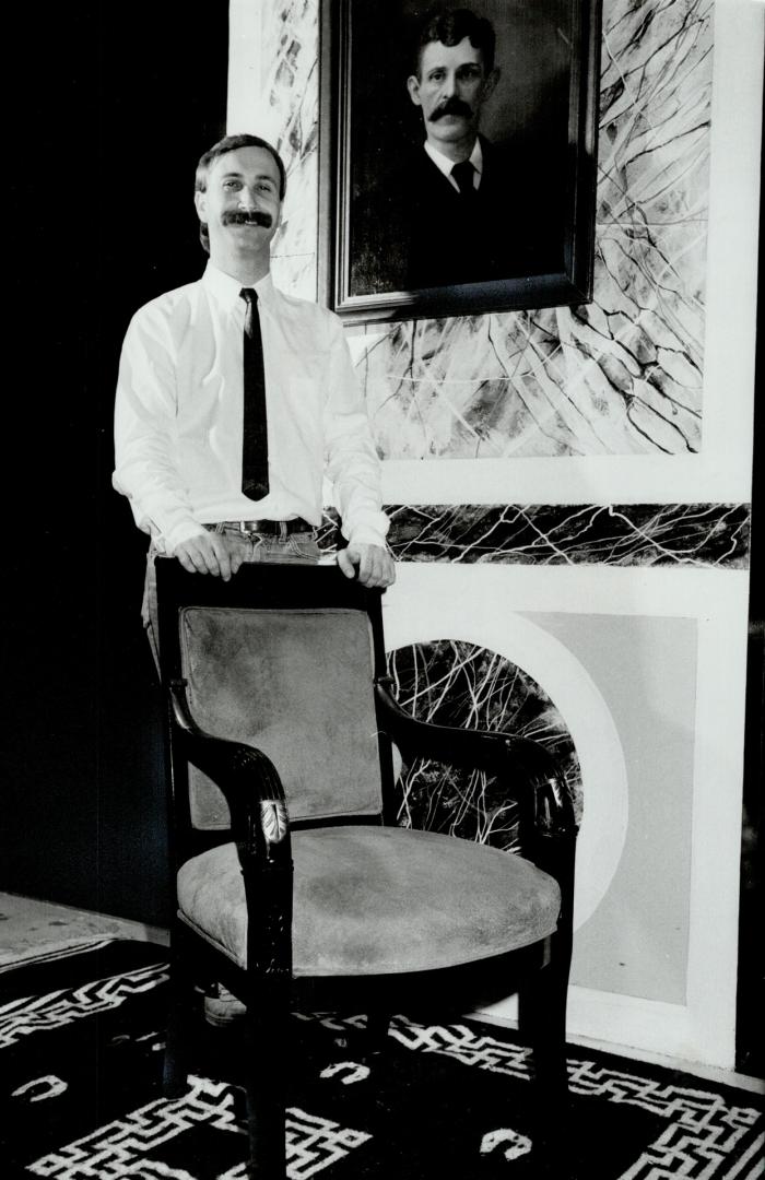 Antique treasure: Neal Small, left, stands in entranceway behind walnut armed chair uphostered in gray suede.