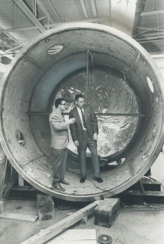 Aeronautics expert Dr. Rod Tennyson (left) shows a revolving tunnel used for testing satellites to Henry McKay at the University of Toronto's Institute for Aerospace Studies. McKay studies unidentified flying objects as a hobby.