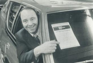 Enthusiastic car dealer Gord Townrow points to copy of American Motor's new warrantly pasted on window of a 1972 model
