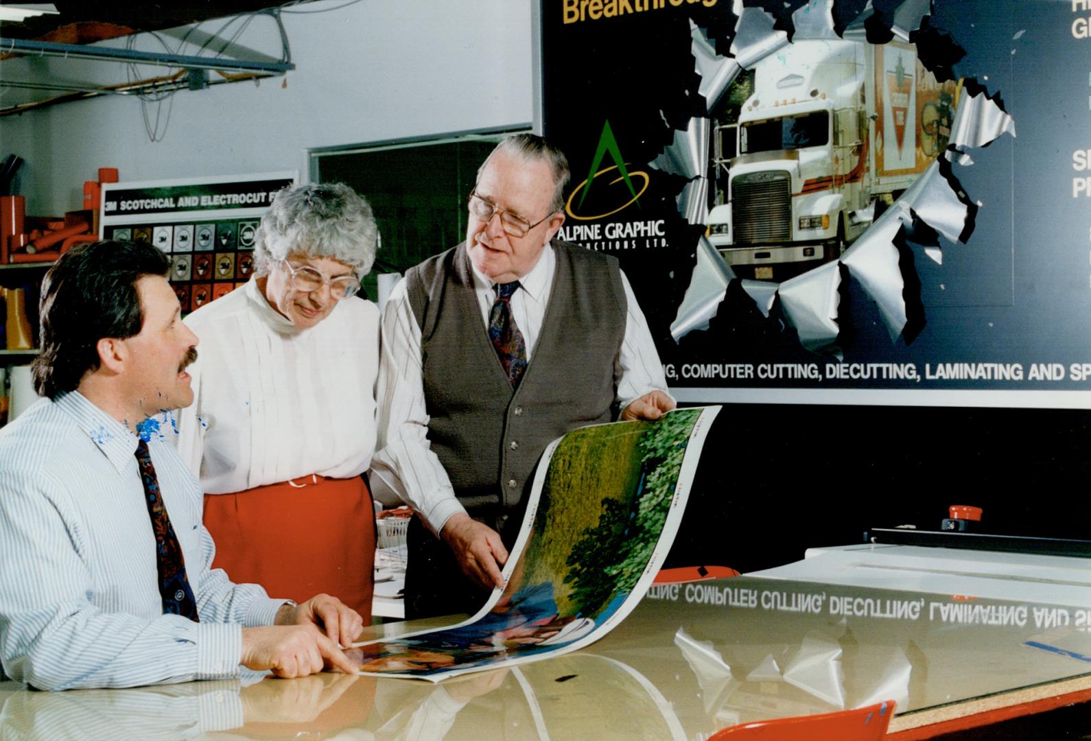Graphic ideas: Sid and Joyce Steele, founders of Alpine Graphics, and company president Ian MacRitchie, look at a billboard-type design they install on the sides of trucks