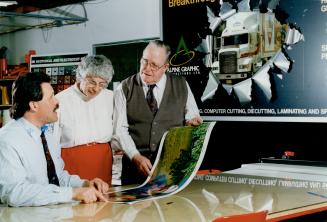 Graphic ideas: Sid and Joyce Steele, founders of Alpine Graphics, and company president Ian MacRitchie, look at a billboard-type design they install on the sides of trucks
