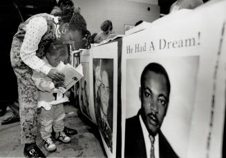 Girl and boy reading book in front of poster of Martin Luther King Junior with text reading He  ...