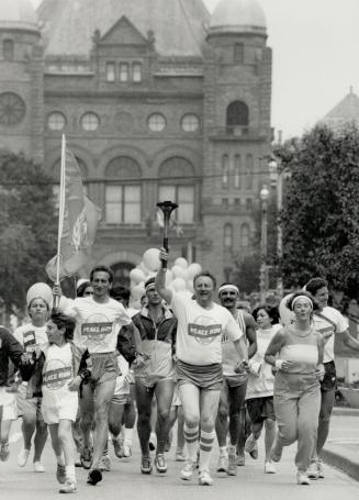 Peace flame: Musician Moe Koffman, a running enthusiast, carries the torch and leads a crowd of peace runners away from Queen's Park on their way to Toronto City Hall