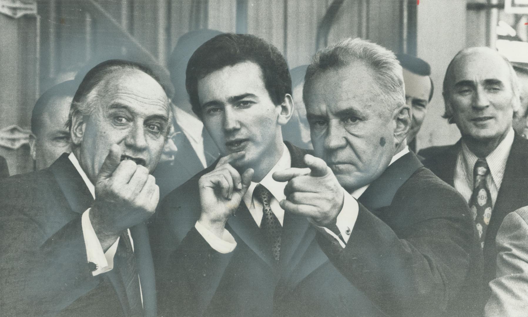 Taking a hard-eyed look at things on the Montreal waterfront, touring Soviet Premier Alexei Kosygin (right) points toward operation he wants to ask Manchester Line shipping official (left) about, while interpreter (centre) translates for him