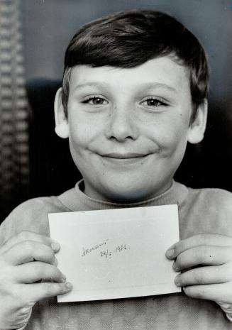 Holding the autograph that Soviet Premier Alexei Kosygin gave to his father, David Coote, an assistant hotel manager at Inn on the Park who served Kosygin a late snack last night, 11-year-old Neil Coote shows the signature
