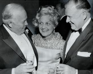 An embarrassing question? Harold Ballard, vice-president of Maple Leaf Gardens, and his wife talk with Controller Allan Lamport (left) during reception following wedding of latter's daughter yesterday