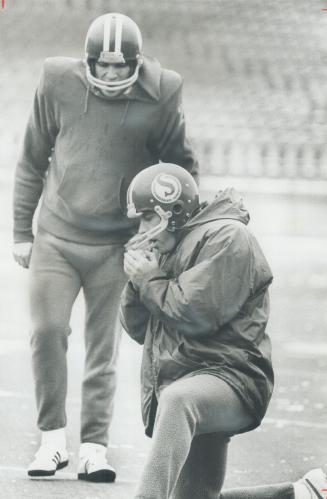 Warming up: Saskatchewan Roughriders' quarterback Ron Lancaster tries to keep his hands warm yesterday as place-kicker Bob Macoritti lines up another practice attempt