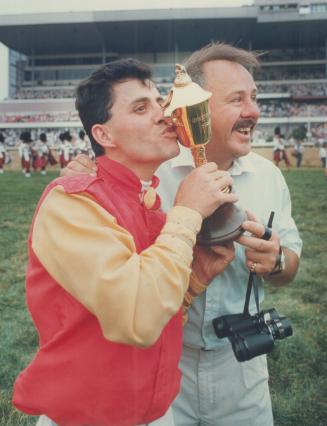 Jockey Jack Lauzon, with his beaming dad Jack, kisses the cup emblematic of winning the Queen's Plate, after riding Regal Intention to victory in the 129th edition of the race yesterday