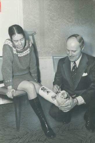 Allan Lawrence, Ontario Conservative leadership candidate, signs his autograph on the cast of campaign worker Mary Ellen Empringham, a Toronto nurse