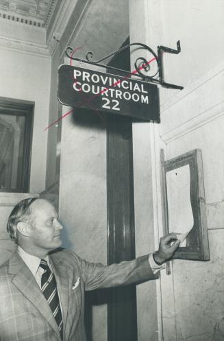 Attorney-General Allan Lawrence checks a notice at Old City Hall today during a surprise visit to inspect cells and courtrooms