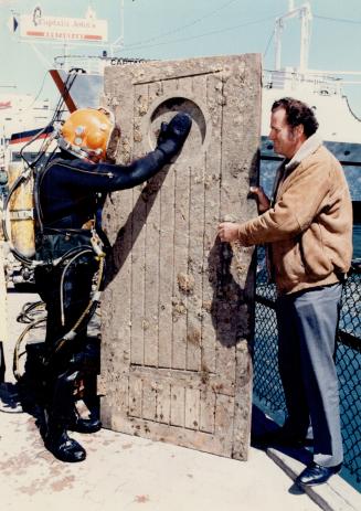 Hull to follow: Diver Frank Sheppard helps Captain John Letnik salvage a door from his sunken marine restaurant, the Normac, which is being raised from Toronto Harbor