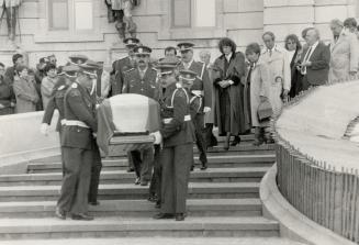 March begins: Quebec police carry the coffin of Rene Levesque, draped in the fleur-de-lis, down the steps of Quebec's National Assembly