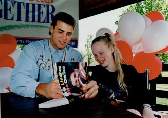 Tara Cooke, 12, smiles as hockey phenom Eric Lindros signs a copy of his autobiography for the patient at North York General Hospital