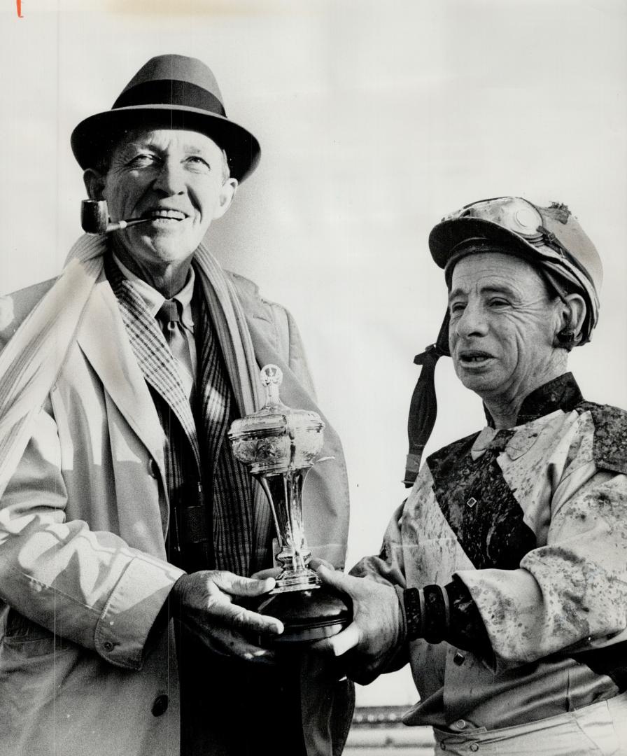 Bing Crosby (left) presents trophy to Johnny Longden. Famed singer congratulates George Royal's rider for victory in Champ