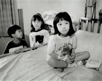 Elizabeth Lue: Six-year-old sits today on bed at the Hospital for Sick Children. Looking on are brother Michael, 5, and another girl.