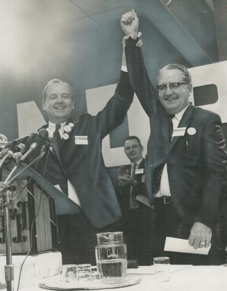 The winner and still leader of Ontario New Democratic Party, Donald MacDonald has his arm raised in victory by his challenger for the leadership, James Renwick (left)