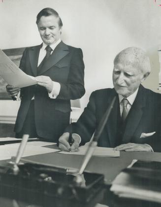 Lieutenant-Governor Ross Macdonald signs into law latest of 131 bills passed by the government of Premier William Davis while the premier watches him