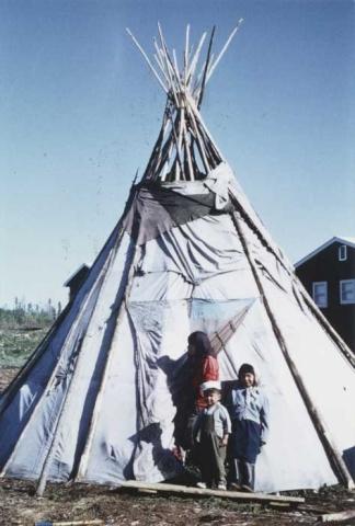 Mother and children standing outside tepee