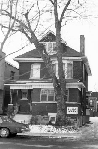 A three-storey brick house next to an alley. There is a tree in the front yard, which is covere ...