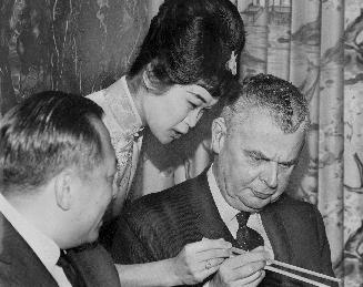 Sweet and sour. Toronto's Chinatown went all out with firecrackers, dragons and lions for visit by Prime Minister Diefenbaker, seen here getting instr(...)