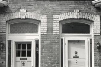 Detail of a duplex-style house. Shows the keystone brickwork surmounting the two front doors, w ...
