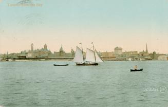 Image shows a few boats on the lake with some buildings in the background.