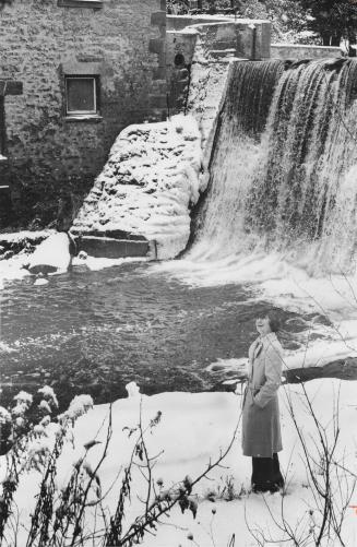 Nicole Barry, one of seven owners of Millcroft Inn, standing next to waterfall, Alton, Ontario