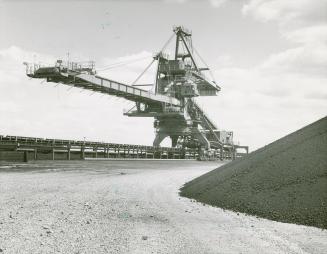 Travelling stacker stockpiling raw materials at Stelco steel plant. Nanticoke, Ont.