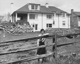 Woman posing in front of a house, Bayview Village, Ontario