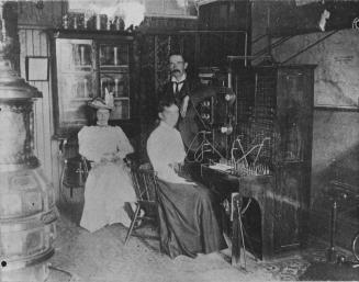 Operators Alice Souch (left) and Annie Trenouth (at the switchboard), and manager Wesley Shaw were the staff of Bell Telephone Company's Bowmanville office in 1898. Bowmanville, Ontario