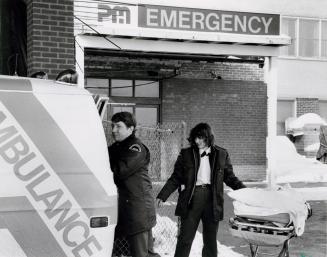 Ambulance attendants Bruce Love and Susan Rohn put the stretcher back into the ambulance at Peel Memorial Hospital. Brampton, Ontario