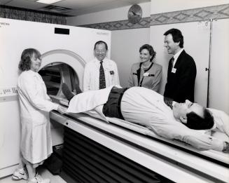 MPP Joe Spina is watched by, from left, Joan Beaumont, co-ordinator of nuclear medicine; radiology chief Samuel Lam; MPP Helen Johns, and Siuemens' chief Albert Goller. Peel Memorial Hospital, Brampton, Ontario