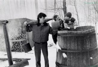 Assistant superintendent Mark Doherty shows how sap used to be collected as Terry Wiegard and his son Brian watch. Bruce's Mill Conservation Area, Ontario