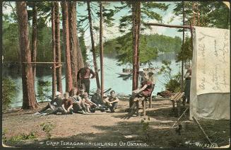 A group of boys sitting outside a tent on the shores of a lake in a wilderness area.