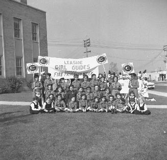 Image shows a group of people posing for a photo on the lawn. they hold a sign that reads: "Lea ...