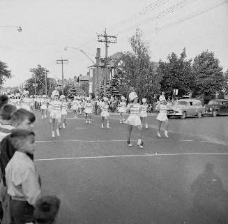 Image shows parade participants marching along the street.