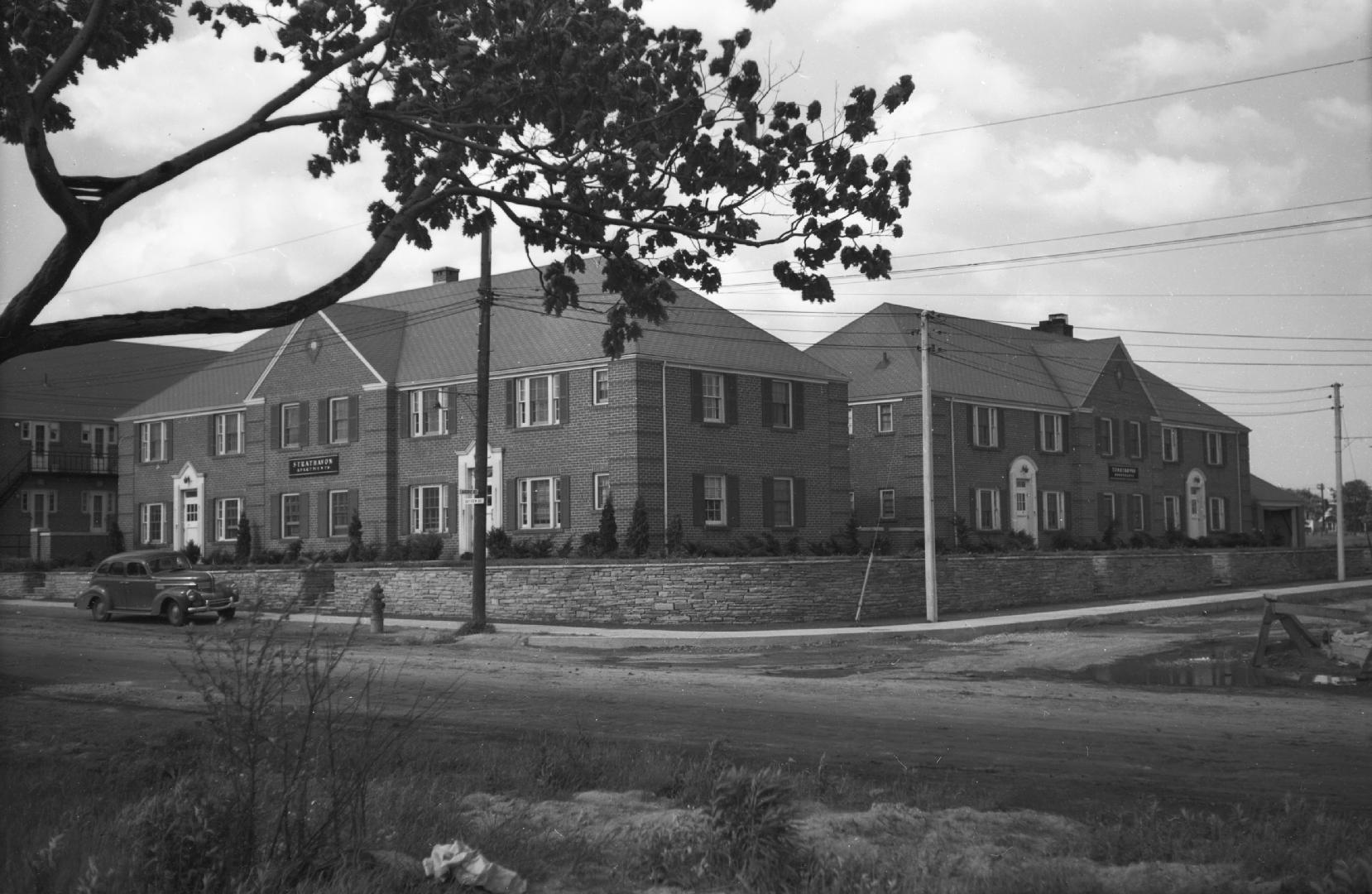 Image shows a street view and a few low rise apartment buildings.