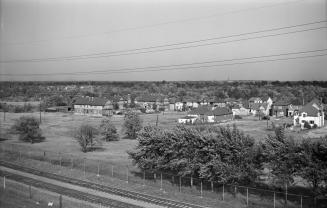 Image shows a track view with some trees and houses on the right side.