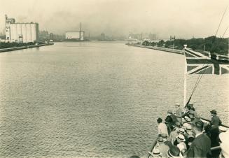 Image shows lake and harbour view. It shows a partial view of the boat with a number of people …