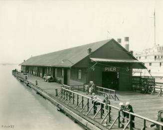 Image shows a wharf and some people around it.