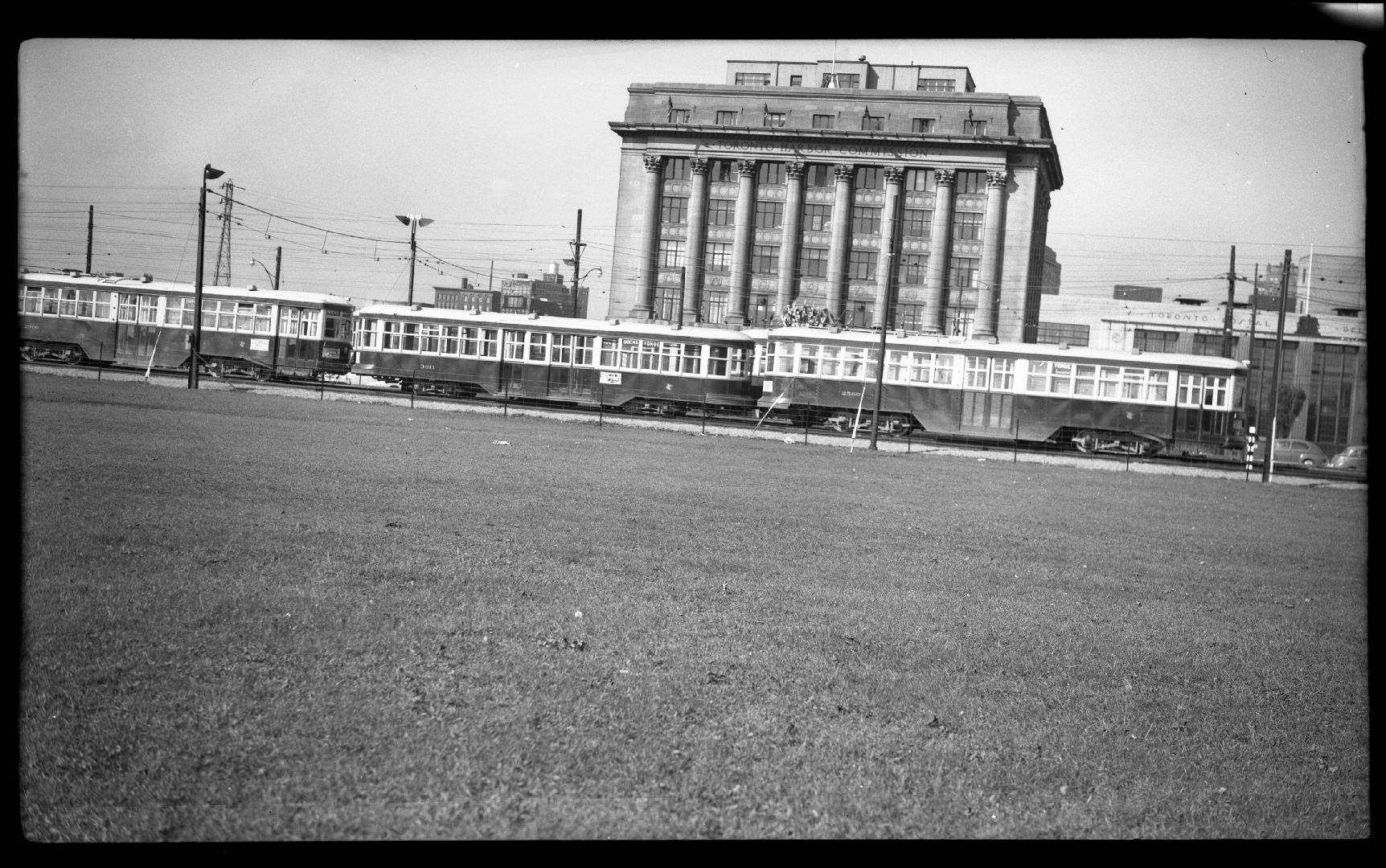 Image shows a multi-floor building with some streetcars in front of it.