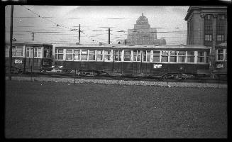 Image shows a few streetcars with some buildings in the background.