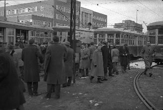 Image shows a number of people at the ferry loop with a few streetcars in the background.