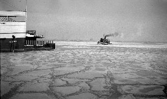 Image shows a steam tugboat approaching in wintertime.