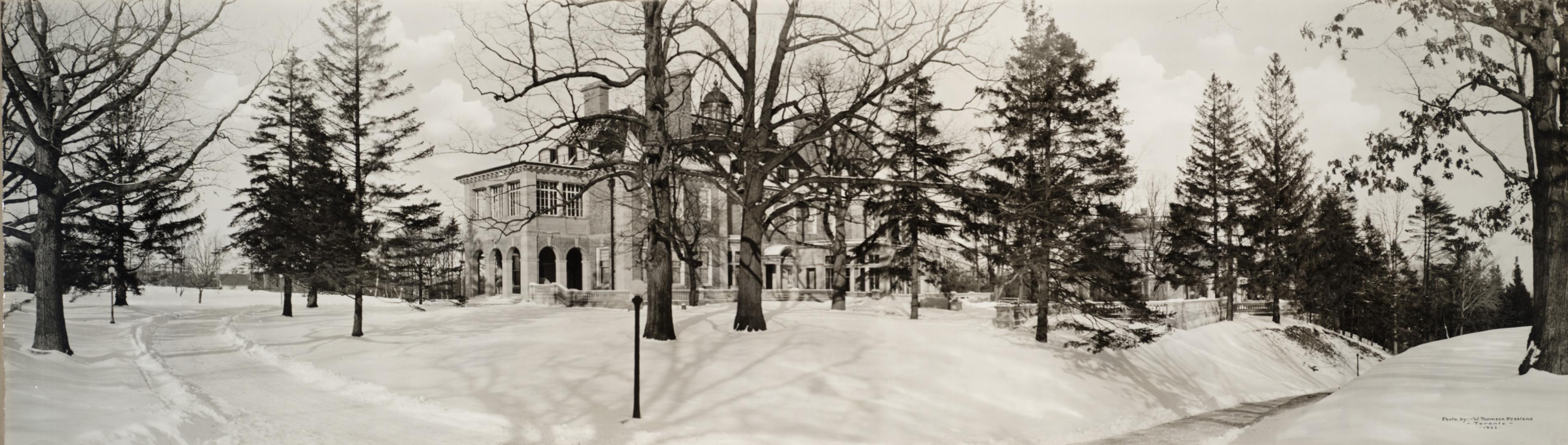 Image shows a limited view of a house in winter. There are a lot of trees around it.
